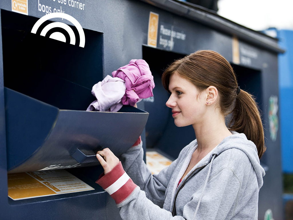 Girl recycles at recycling station where waste container sends a signal if need for emptying